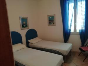 una camera con due letti e una finestra con tende blu di Casa vacanze otranto a Otranto