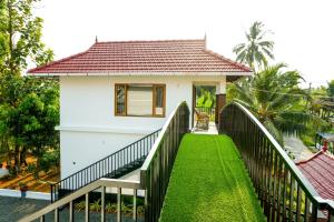 a small white house with a black fence at Coconut Palms Village Homestay in Kumarakom
