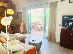 a living room with a couch and a tv and a table at Espacioso Bungalow en Maspalomas in Maspalomas