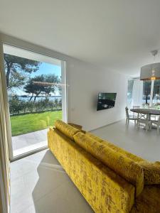 een woonkamer met een gele bank en een televisie bij Stunning villa with pool and lagoon view in Palazzo Vianello