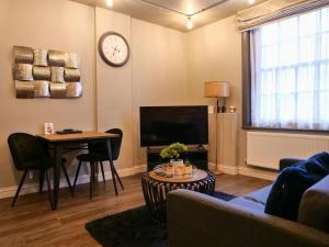 een woonkamer met een tafel en een klok aan de muur bij Luxe 2 Bed Apt - City Centre - Office - SmartTVs in Birmingham