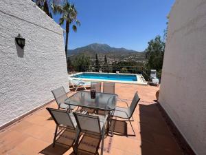 eine Terrasse mit einem Tisch, Stühlen und einem Pool in der Unterkunft Cd-1383 Three Bedroom Villa With Pool in Viñuela