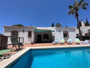 einen Pool mit zwei Stühlen und ein Haus in der Unterkunft Cd-1383 Three Bedroom Villa With Pool in Viñuela