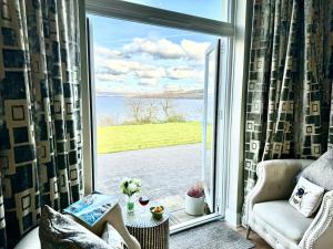 una sala de estar con una gran ventana con vistas al agua en Loch View at Lomond Castle en Balloch