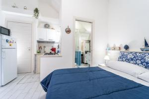 a white bedroom with a blue bed and a kitchen at Casa di Cecilia in Castellammare del Golfo