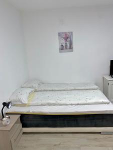 uma cama num quarto com uma parede branca em Apartman Bogdan em Čačak