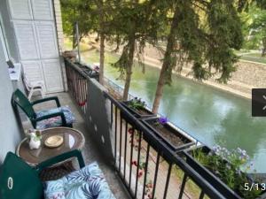 uma varanda com uma mesa e cadeiras ao lado de um rio em Apartman Bogdan em Čačak