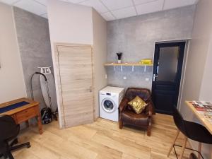 een wasruimte met een wasmachine en een stoel bij Aux frais de la princesse - Gîte citadin 3 épis in Chimay