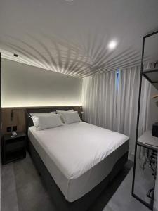 a bedroom with a large white bed with white pillows at Brava Mundo Hotel Boutique in Itajaí