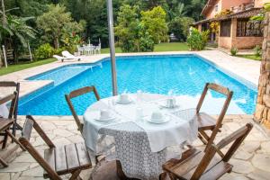 uma mesa e cadeiras ao lado de uma piscina em Recanto da Rose Guesthouse em Caraguatatuba