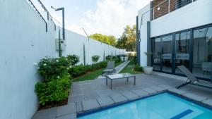 a patio with a pool and chairs next to a building at Chic Modern Midrand Escape in Midrand