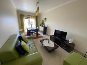 a living room with a green couch and a television at APARTAMENTO VISTA MAR in Lourinhã