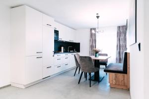een keuken met witte kasten en een tafel met stoelen bij Fonses Chalet in Waging am See