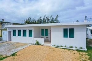 a white house with green windows at Centrally located Villa with 3 Pools -Food & Beach walking distance in Arecibo