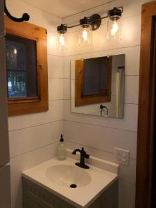 een badkamer met een wastafel en een spiegel bij Little Red Wing 50s Lake Cabin in Bradford