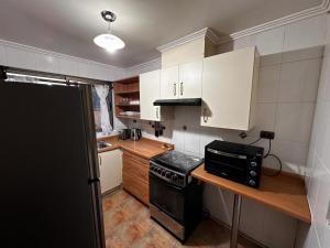 una pequeña cocina con estufa negra y armarios blancos. en Casa en San Pedro de la Paz, 5 personas, 2 dormitorios, gimnasio, en San Pedro de la Paz
