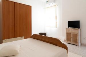een slaapkamer met een bed, een kast en een televisie bij Casa Duesse in Orosei