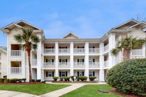 a large white building with palm trees in front at River Oaks 10D in Myrtle Beach