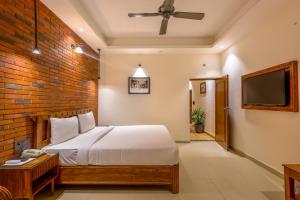 a bedroom with a bed and a brick wall at Hotel Lalit Palace in Dehradun
