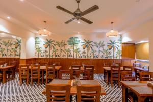 restauracja z drewnianymi stołami i krzesłami oraz palmami na ścianie w obiekcie Hotel Lalit Palace w mieście Dehradun