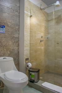 a bathroom with a toilet and a glass shower at Waira Suites in Leticia