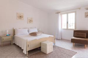 een witte slaapkamer met een bed en een stoel bij Casa Duesse in Orosei