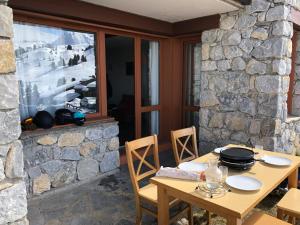 a wooden table and chairs in front of a stone wall at Studio 28m2 vue pistes plein sud du dimanche au dimanche in La Plagne