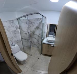 a bathroom with a toilet and a shower and a sink at Hotel Plaza Paris in Calarcá