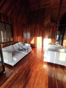 My Country House Paradise, Rio Celeste! في San Rafael: غرفة معيشة بها كنبتين بيضاء وأرضية خشبية