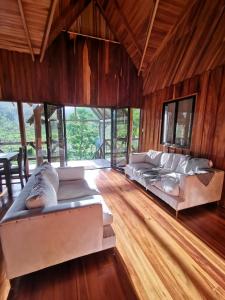 uma sala de estar com 2 sofás e um piso de madeira em My Country House Paradise, Rio Celeste! em San Rafael