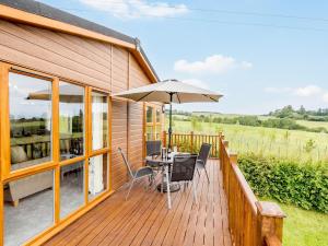 a wooden deck with a table and an umbrella at 2 Bed in Kinlet 92657 in Kinlet