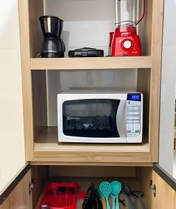 a microwave oven sitting inside of a kitchen cabinet at 103 - Apartamento Completo Para Até 5 Hóspedes in Patos de Minas