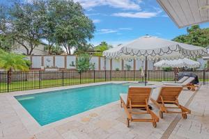 a swimming pool with two chairs and an umbrella at SOUTHERN SEABREEZE 5BR POOL & BEACH by Barclé in Rosemary Beach