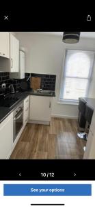 uma cozinha com armários brancos e piso em madeira em Cosy central apartment near Stokes Croft em Bristol