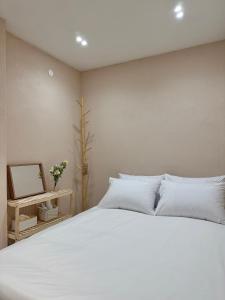 1 dormitorio con 1 cama blanca grande y espejo en Hoho House en Busan