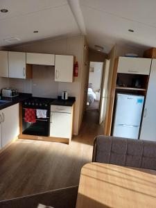 ブラックプールにあるCaravan Holiday Home @ Marton Mere, BLACKPOOLの白いキャビネットとソファ付きのキッチンが備わります。