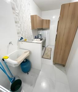 uma pequena cozinha branca com um lavatório e um balcão em 104 - Apartamento Completo para até 7 Hóspedes em Patos de Minas