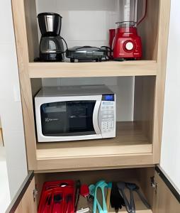 a microwave on a shelf in a kitchen at 104 - Apartamento Completo para até 7 Hóspedes in Patos de Minas