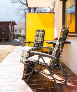 twee stoelen op een patio met een gele muur bij Hotel Garni Effland in Bayrischzell