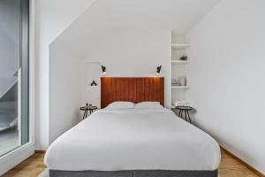 a bedroom with a white bed with a wooden headboard at Luxury 2BR, Free Parking, Balcony in Luxembourg