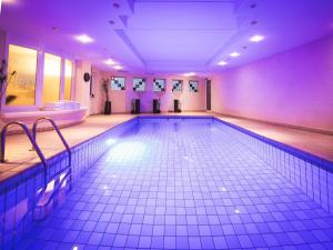 a large swimming pool in a room with purple lighting at Hotel Panorama in Rablà