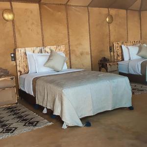 a bedroom with two beds in a tent at Sahara Luxurious Camp in Merzouga