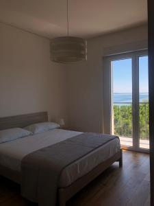a bedroom with a bed and a large window at Finestra sul mare in Monfalcone