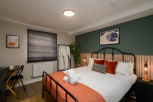 una camera da letto con un grande letto bianco con cuscini arancioni di Benjamin Suite by Koya Homes - 3 Bedrooms - Cardiff a Cardiff