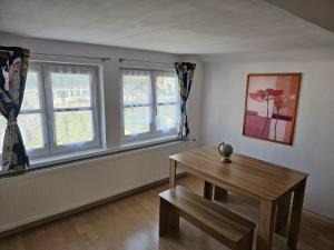 una camera con un tavolo in legno e due finestre di Ferienwohnung Attersee a Steinbach am Attersee