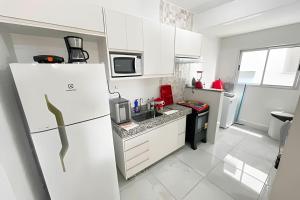 La cuisine blanche est équipée d'un réfrigérateur et d'un évier. dans l'établissement 202- APARTAMENTO de 2 QUARTOS para até 5 HÓSPEDES, à Patos de Minas