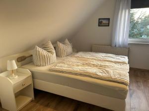 1 dormitorio con cama con almohadas y ventana en Strandkojen en Trassenheide