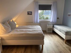 sypialnia z 2 łóżkami i oknem w obiekcie Strandkojen w Trassenheide