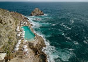 a swimming pool on a cliff next to the ocean at UNA HOTELS Capotaormina in Taormina