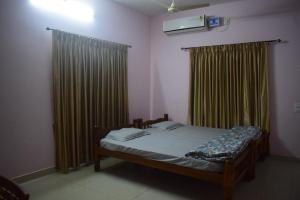 a bedroom with a bed and curtains and a tv at Delta Hospitality - Sea facing rooms with a PRIVATE BEACH in Kalyānpur